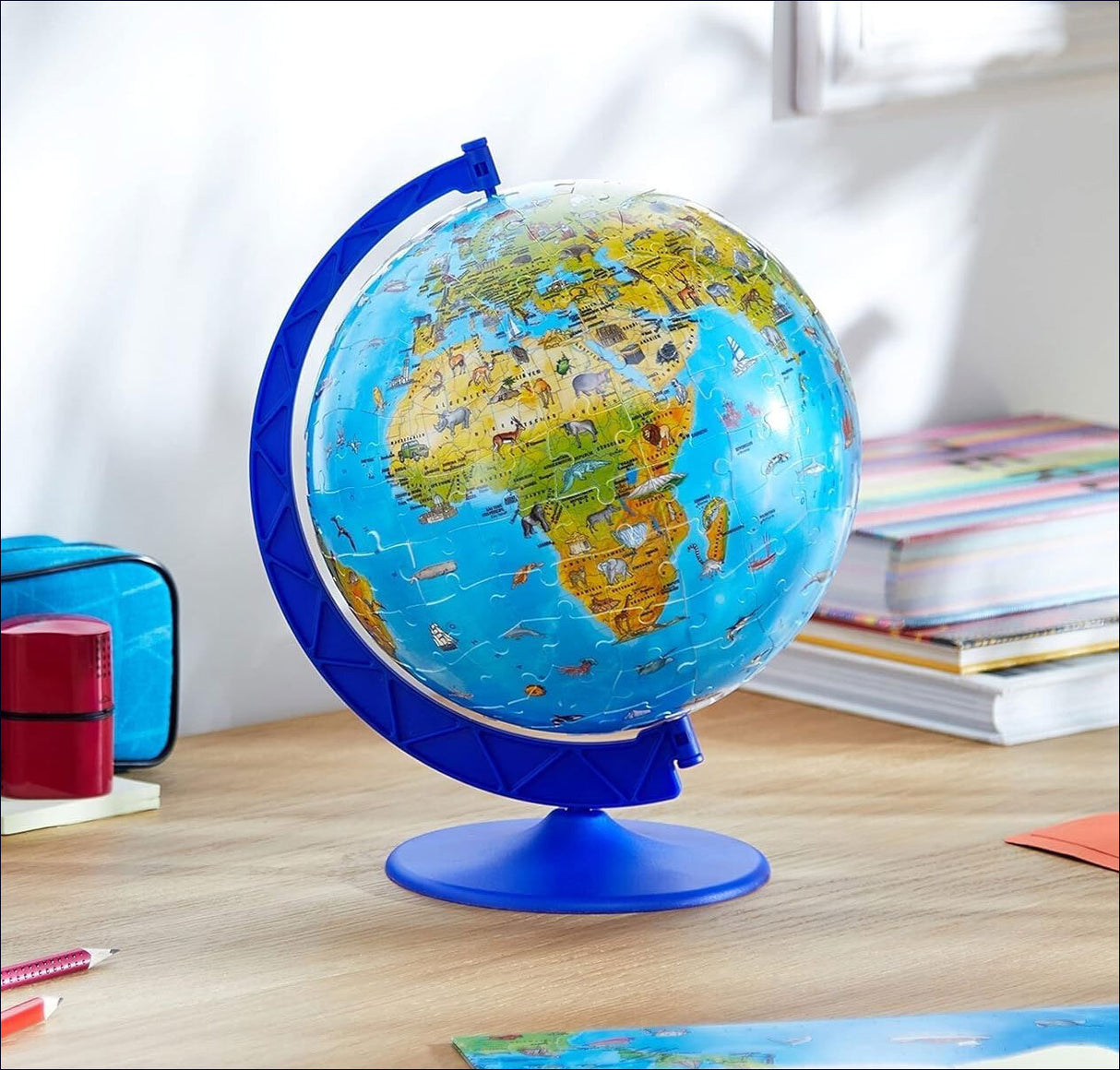 Ein Globus auf einem Schreibtisch, zeigt Afrika, Europa und Südamerika, umgeben von Schulmaterialien.