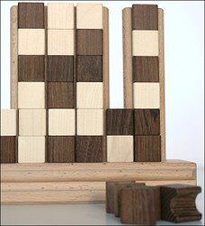 Holzklötze in verschiedenen Brauntönen auf einer Holzplatte, einige liegen davor.