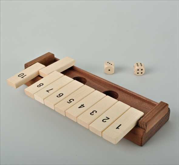 Mahjong-Spiel mit nummerierten Steinen, zwei Würfeln und Holzrahmen auf hellem Hintergrund.