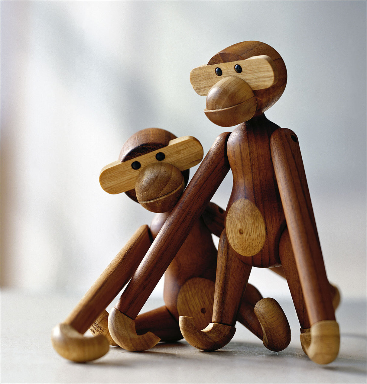 Zwei aus Holz gefertigte Affenfiguren, sitzend und nebeneinander, mit runden Köpfen und schwarzen Augen.