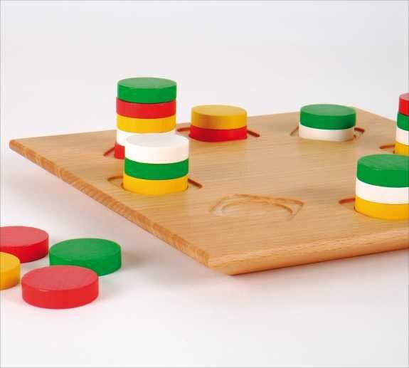 Holzbrett mit bunten, gestapelten Spielscheiben in Rot, Grün, Weiß und Gelb.