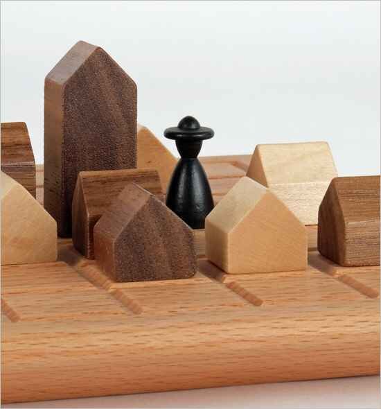 Schachfigur auf einem Holz-Schachbrett mit Holzhäusern als Figuren.