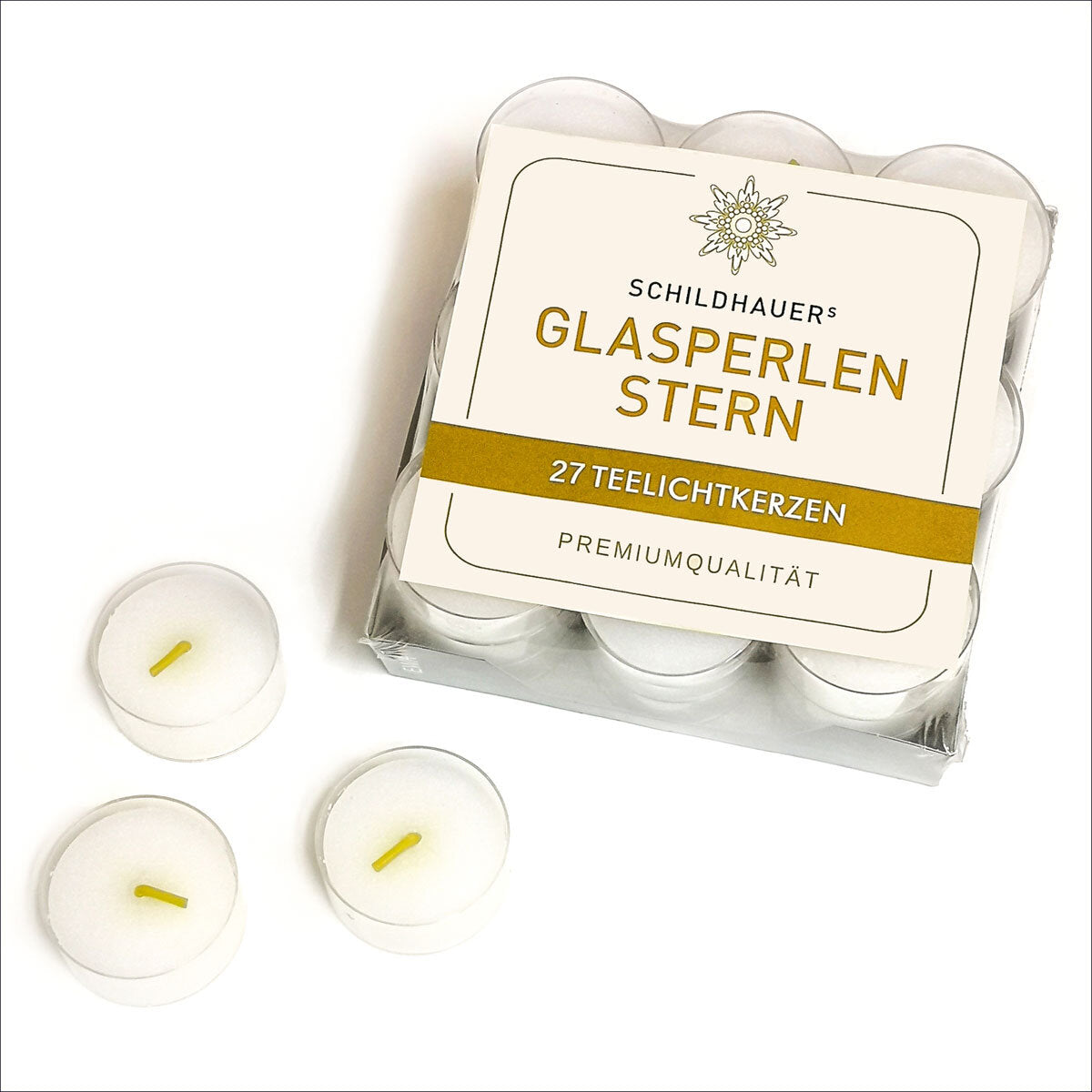 Packung mit 27 weißen Teelichtkerzen, drei Kerzen außerhalb der Verpackung.