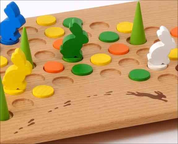 Holzbrett mit bunten Spielsteinen, Figuren und Vertiefungen für ein Brettspiel.
