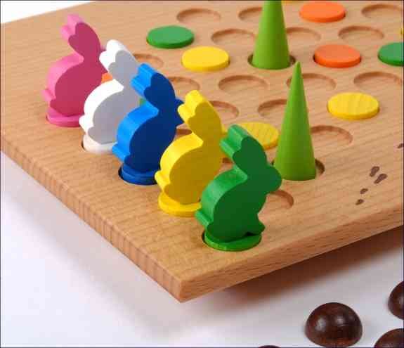 Brettspiel mit bunten Hasen-Figuren, Spielsteinen und grünen Spielfiguren auf Holzbrett.