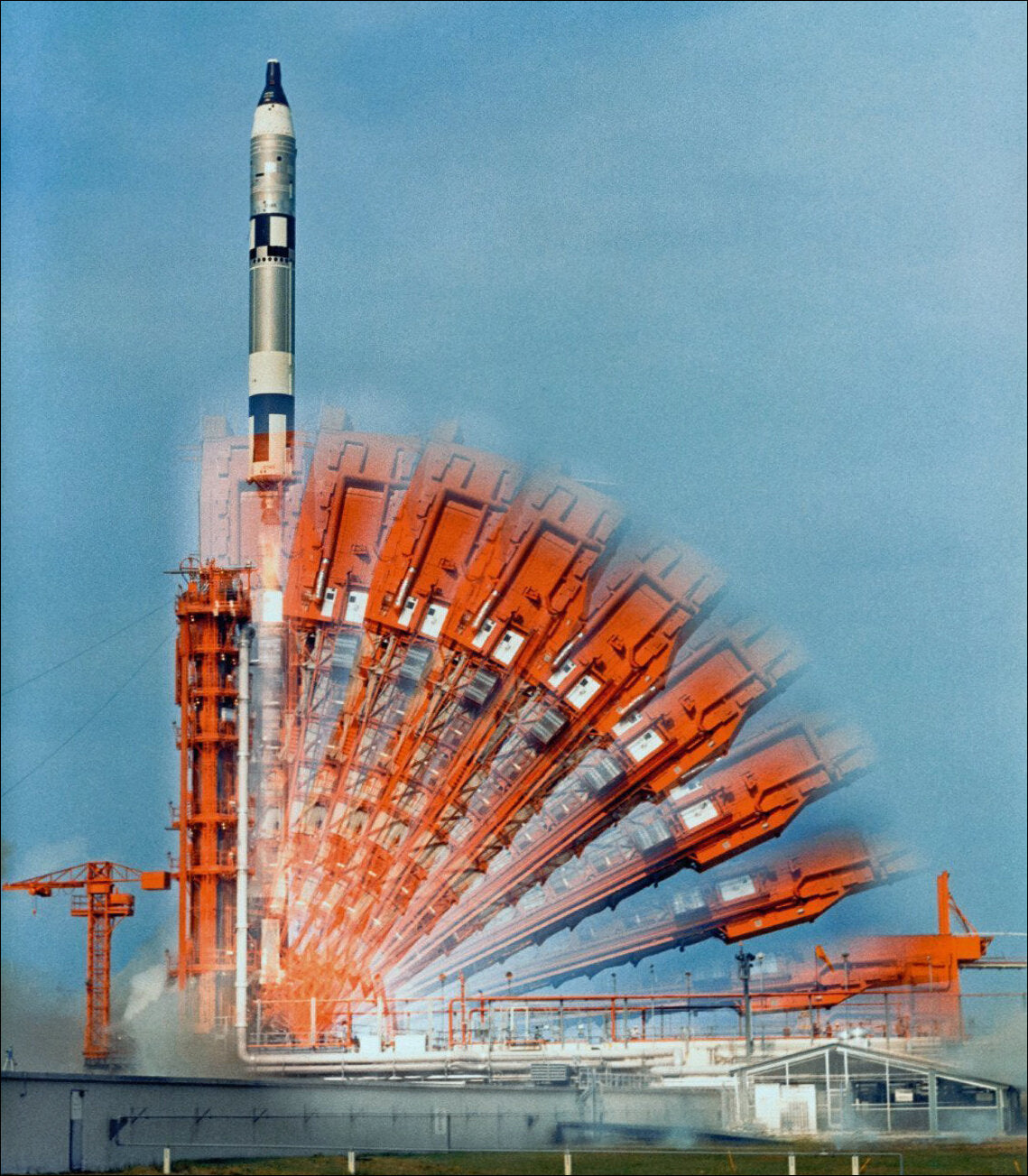 Startbahn eines Raketenstartplatzes mit rot-orangefarbenen Startvorbereitungen und Rakete im Himmel.