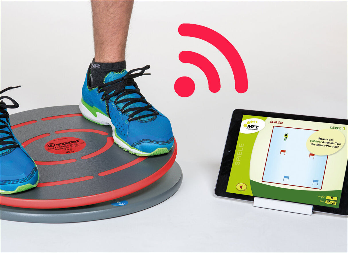 Blaue Sportschuhe auf einer Balanceplatte, daneben ein Tablet mit Skisprungspiel, rotes Wi-Fi-Symbol im Hintergrund.