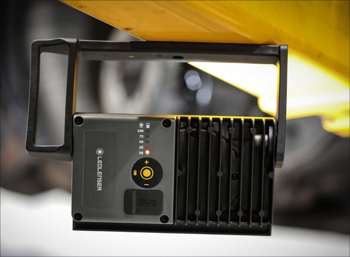 Lichtquelle mit Einstellknopf, Batteriestatus und Leuchtkraftanzeige, auf Tisch montiert.