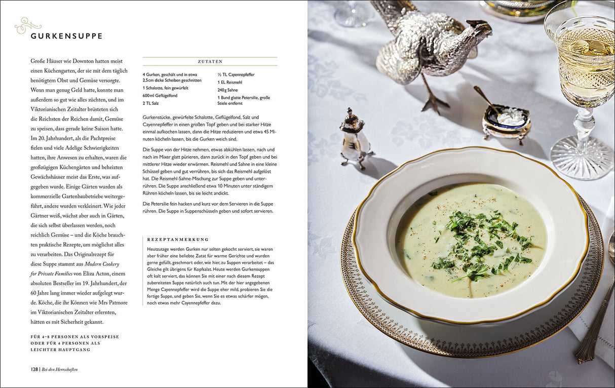 Gurkensuppe in einer weißen Schale mit goldener Verzierung, daneben ein silberner Vogel, Gläser mit Getränk