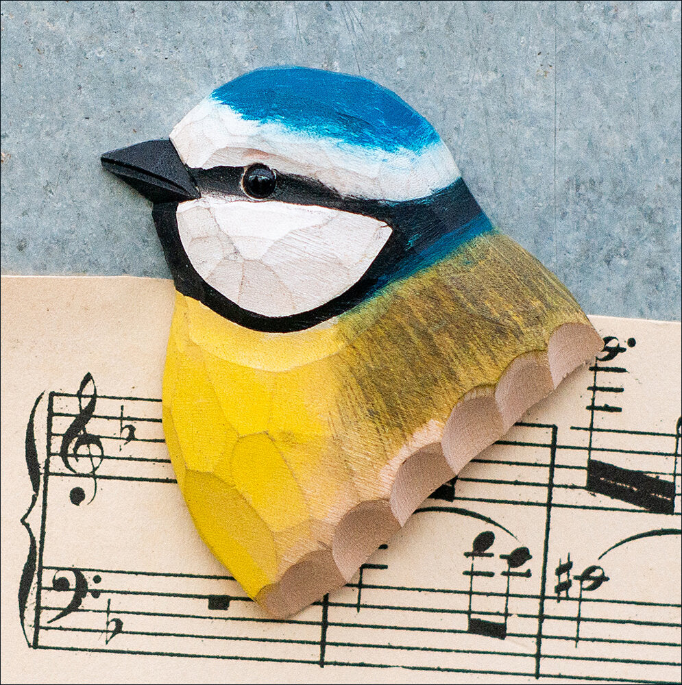 Holzschnitt eines bunten Vogelkopfs auf Notenblatt.