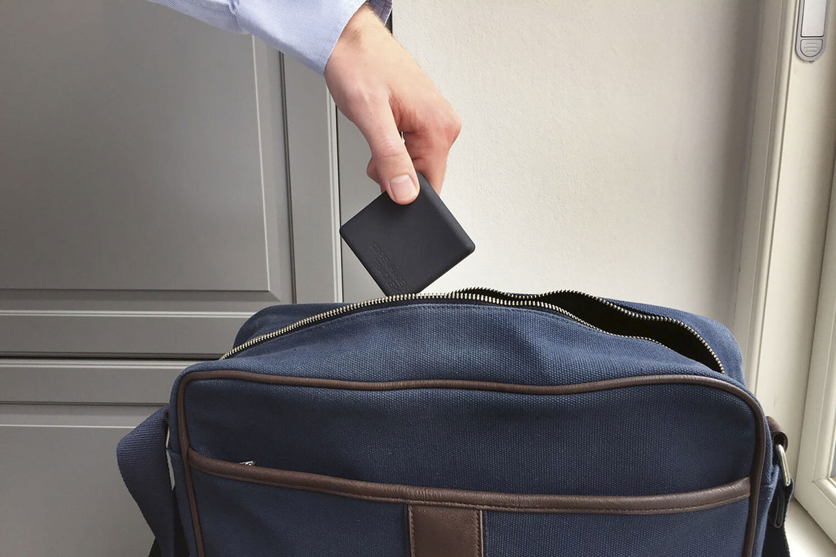 Hand steckt Geldbörse in eine Tasche eines Rucksacks.