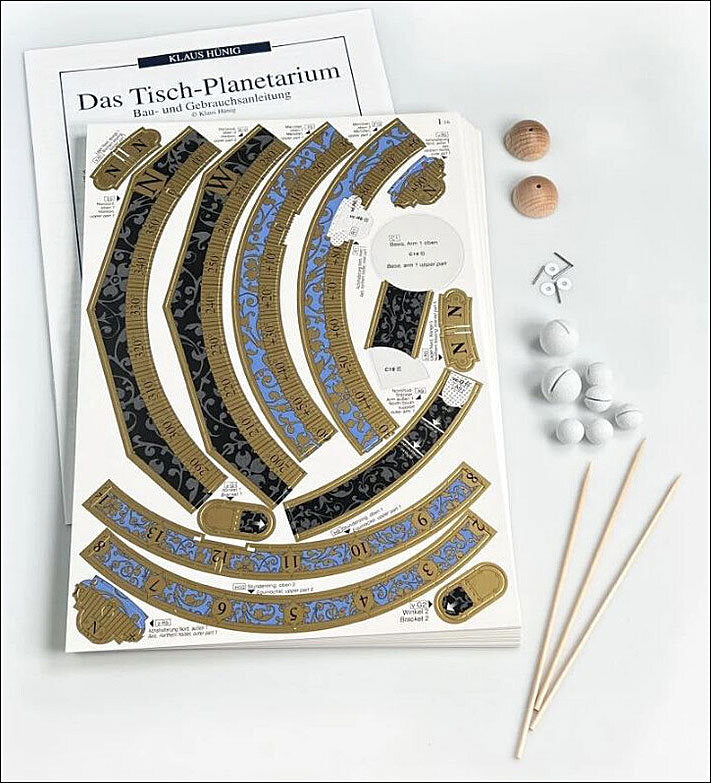 Bauanleitung für ein Tisch-Planetarium, mit Papierteilen, Holzstücken, Kugeln, Schrauben und Stäbchen.