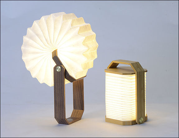 Zwei Lampen mit Holzrahmen und gefalteten Papier-Schirmen, eine steht, die andere liegt.