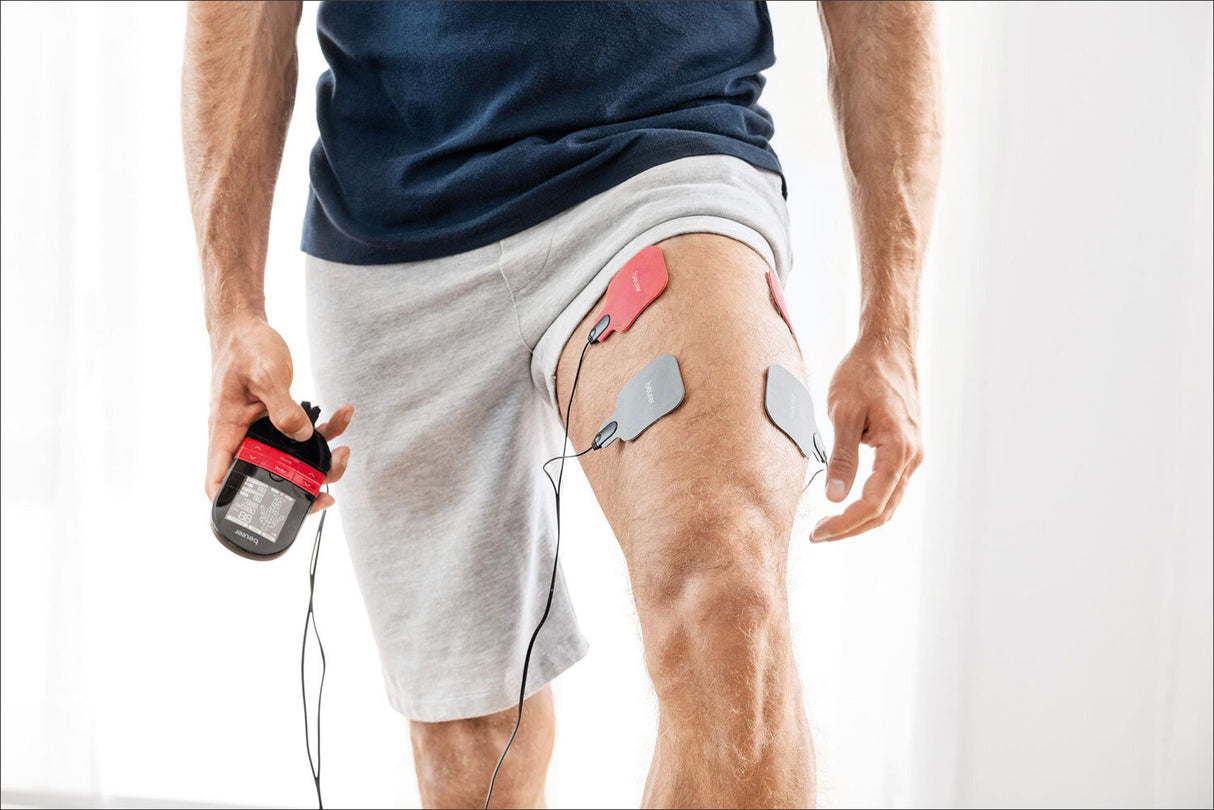 Mann mit EKG-Elektroden am Oberschenkel, hält ein tragbares EKG-Gerät in der Hand.