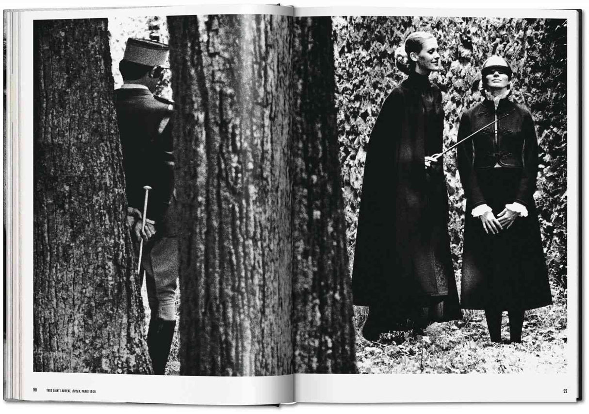 Zwei Frauen in dunklen Kleidern und eine Person in Militäruniform im Wald, mit Bäumen im Hintergrund.