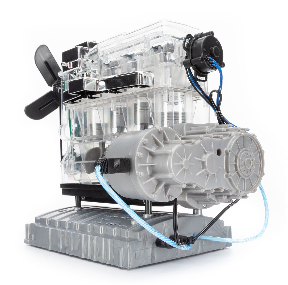Transparentes mechanisches Modell mit Motor, Kabeln und schwarzen Komponenten auf grauem Sockel.