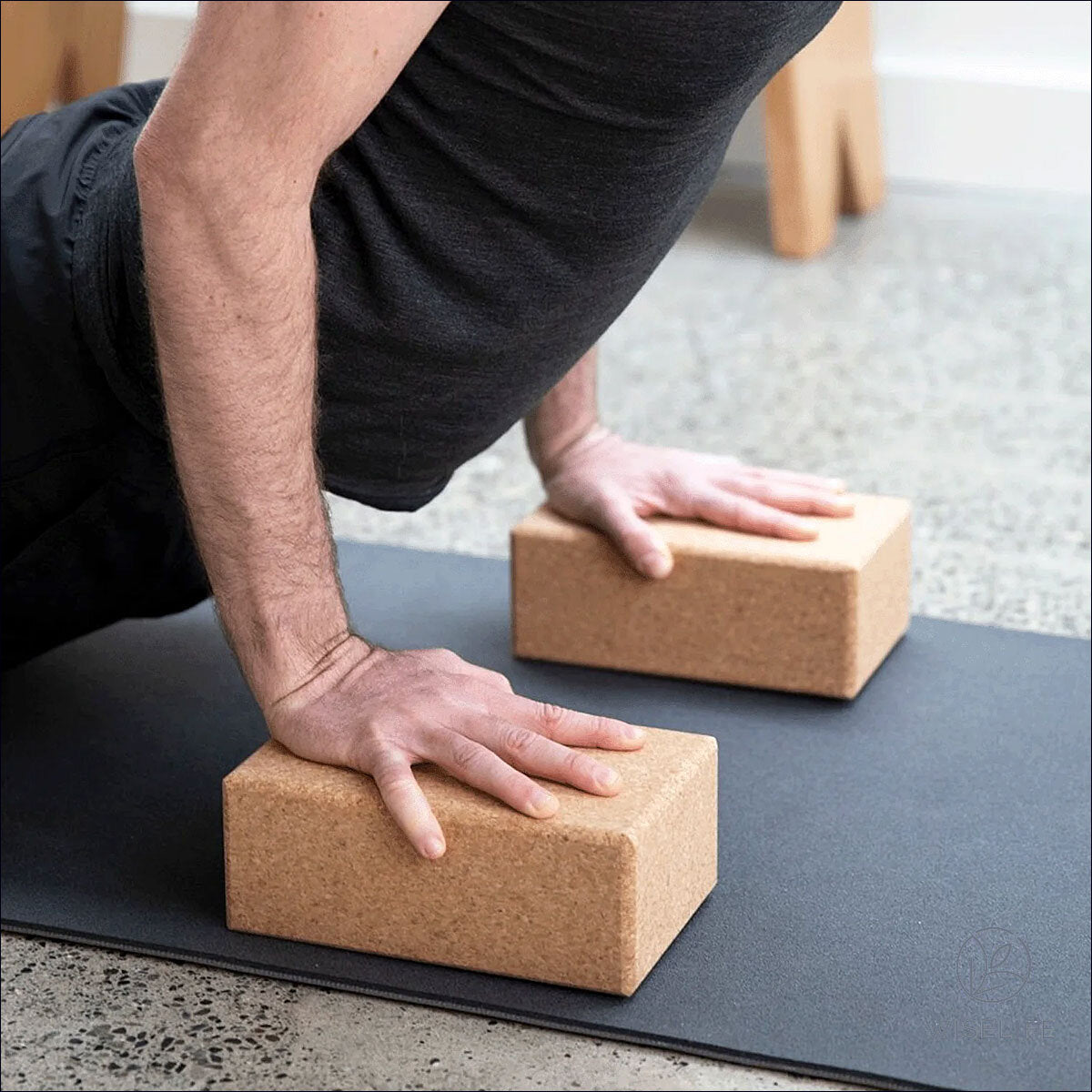 Person in Yoga-Position auf Händen und Füßen, Hände auf Yoga-Blöcken, im Raum.