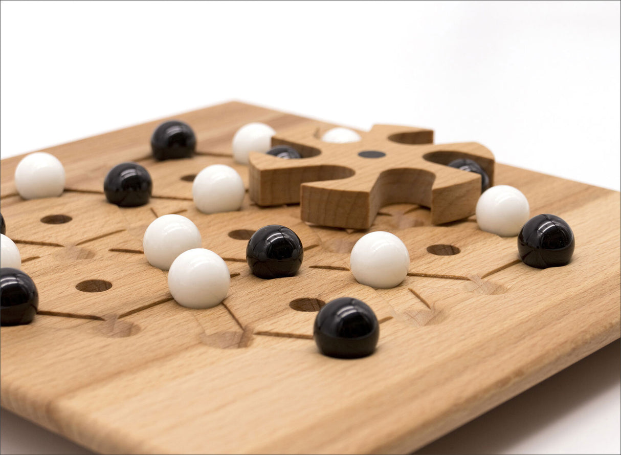 Holzbrett mit schwarzen und weißen Kugeln, einem Holzpuzzle-Teil und einem Spielfeld.