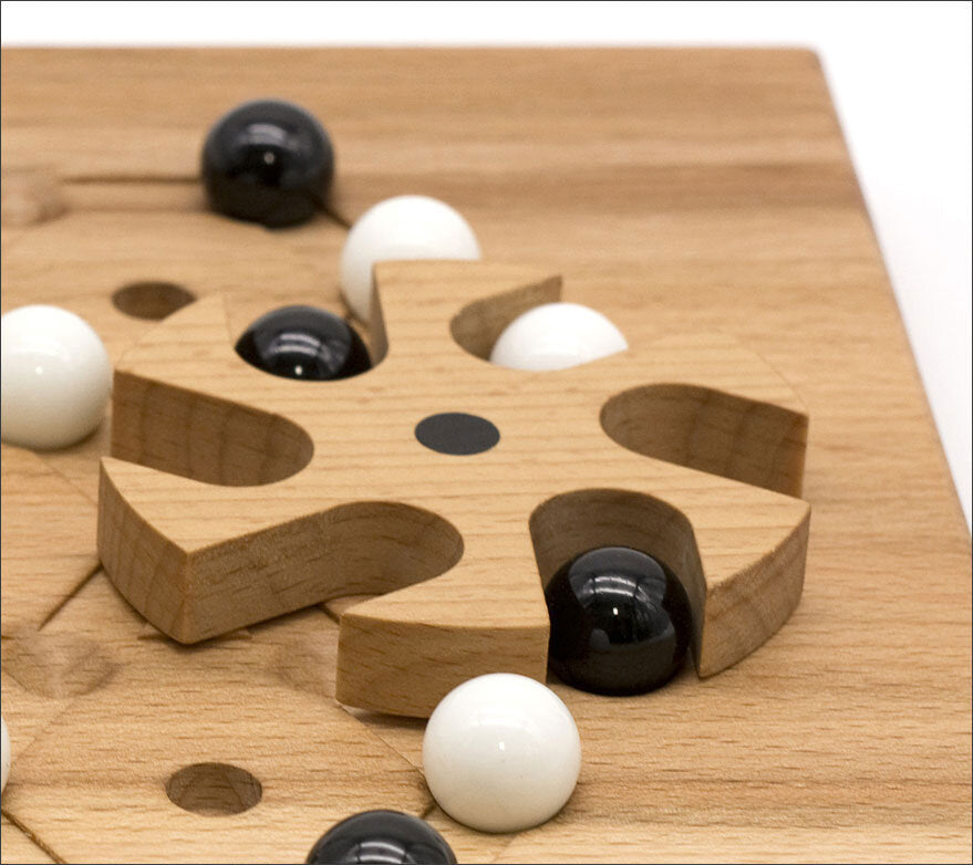 Holzspielbrett mit schwarzen und weißen Kugeln, die in Vertiefungen liegen.