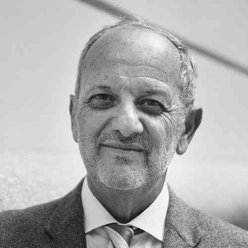 Schwarz-weiß-Bild eines älteren Mannes mit grauem Haar, Bart und Anzug.