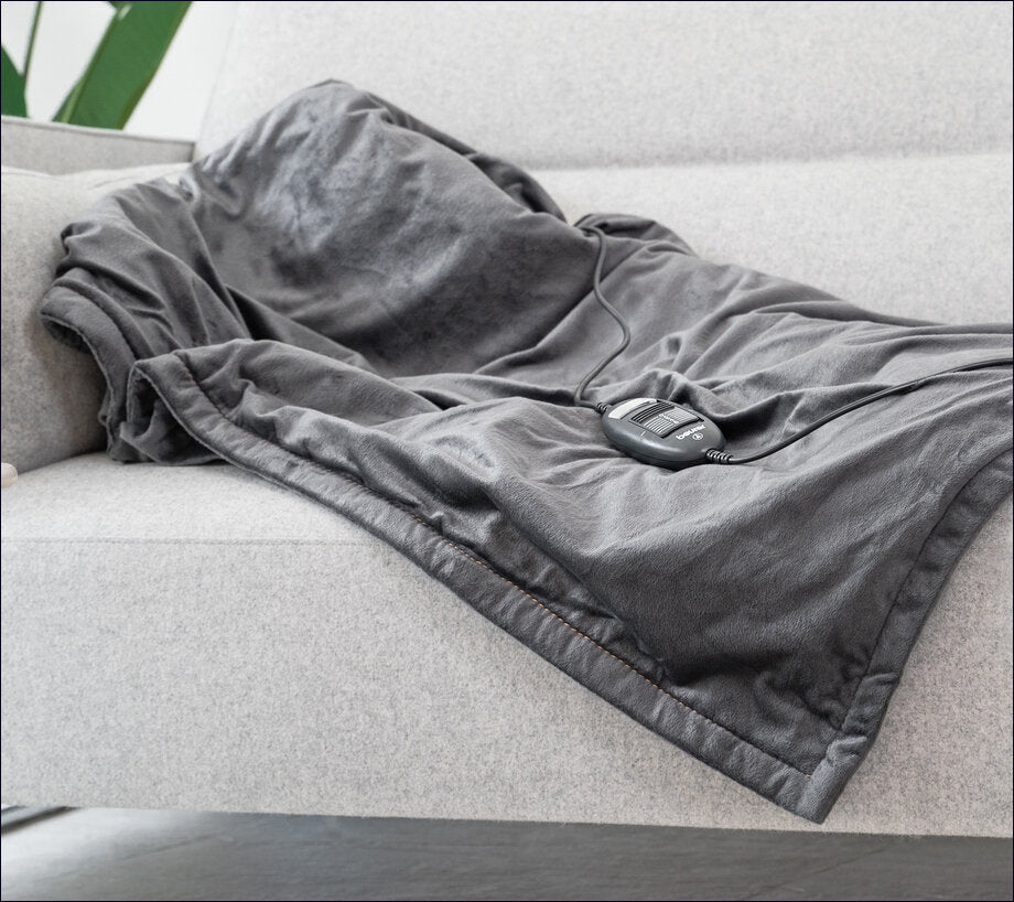 Ein graues Sofa mit einer Decke und einem EKG-Überwachungsgerät auf der Decke.