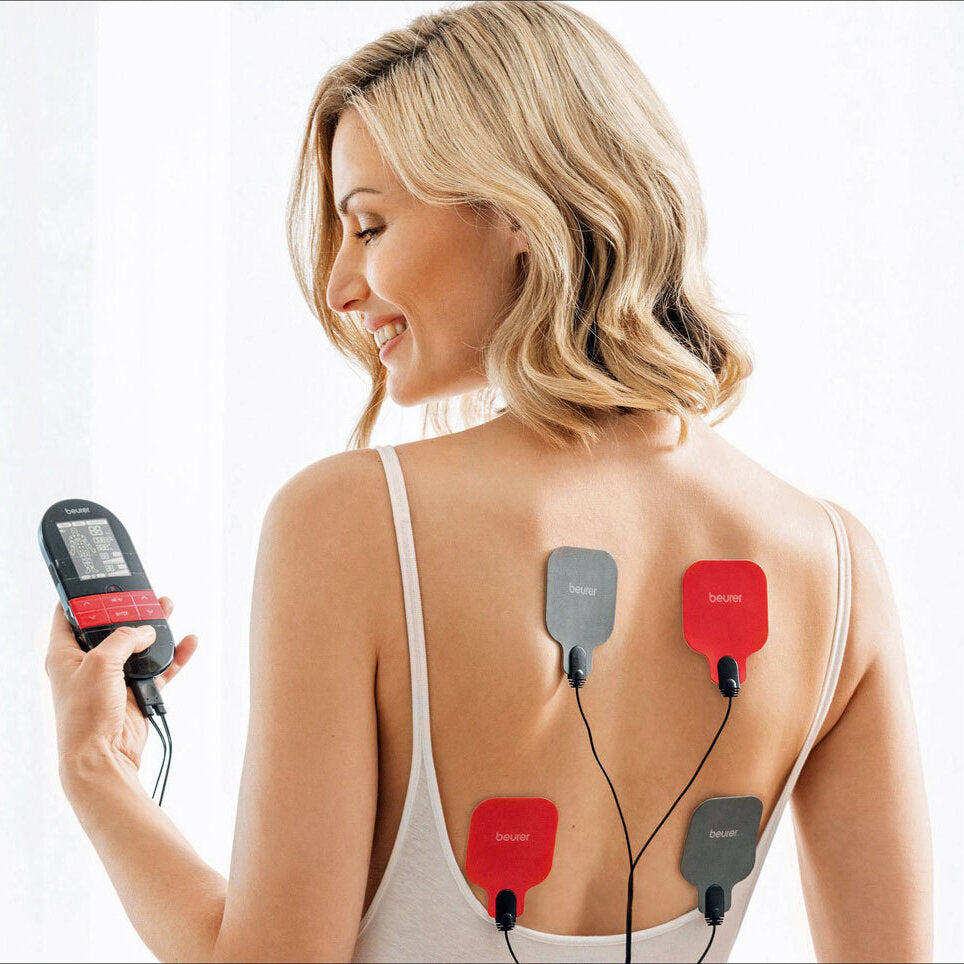 Frau mit vier Elektroden auf dem Rücken, die an ein Gerät gehalten wird.