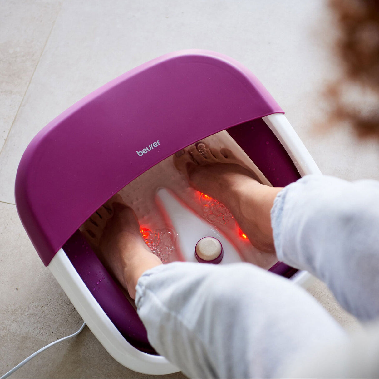 Personen stehen in einer Fußbadewanne mit roten Lichtern, Füße sind eingetaucht.