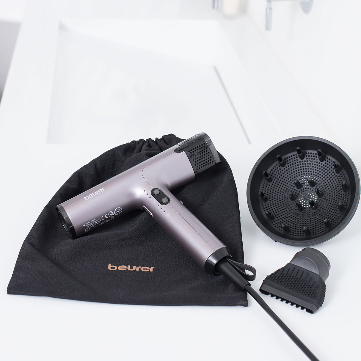 Handstaubsauger, Aufsätze und Tragetasche auf weißem Tisch.