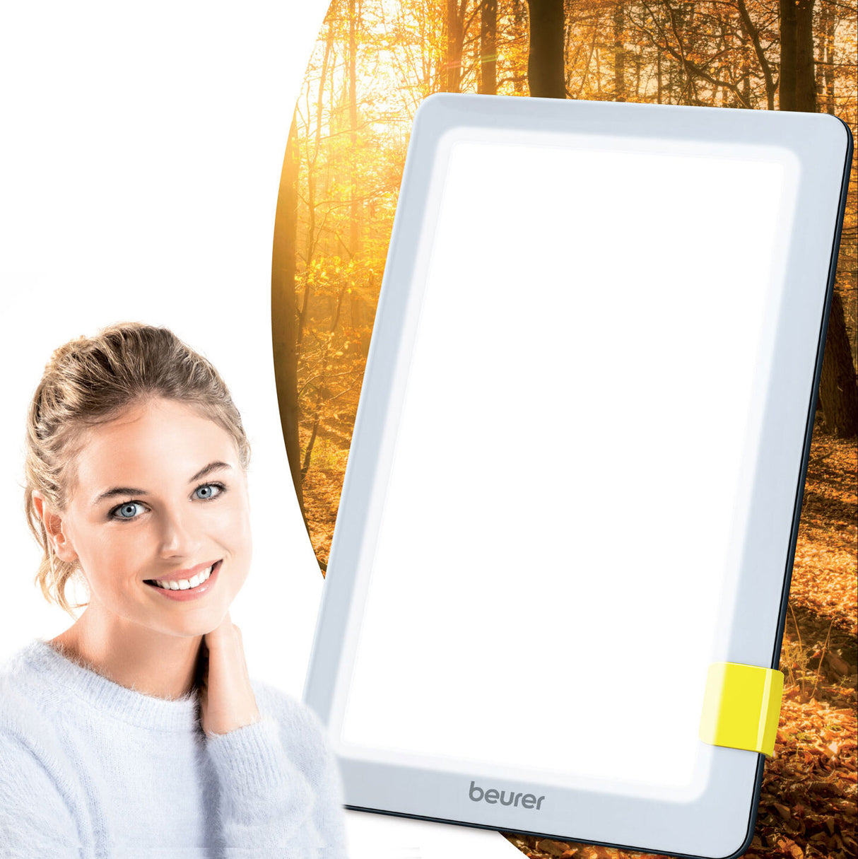 Junge Frau mit blondem Haar vor einem weißen Beurer-Lichttherapiegerät, im Hintergrund ein herbstlicher Wald.