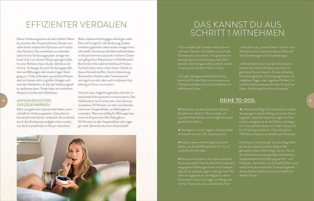 Frau sitzt auf Sofa, isst Beeren aus Schüssel, schaut in Kamera, im Hintergrund helles Zimmer.