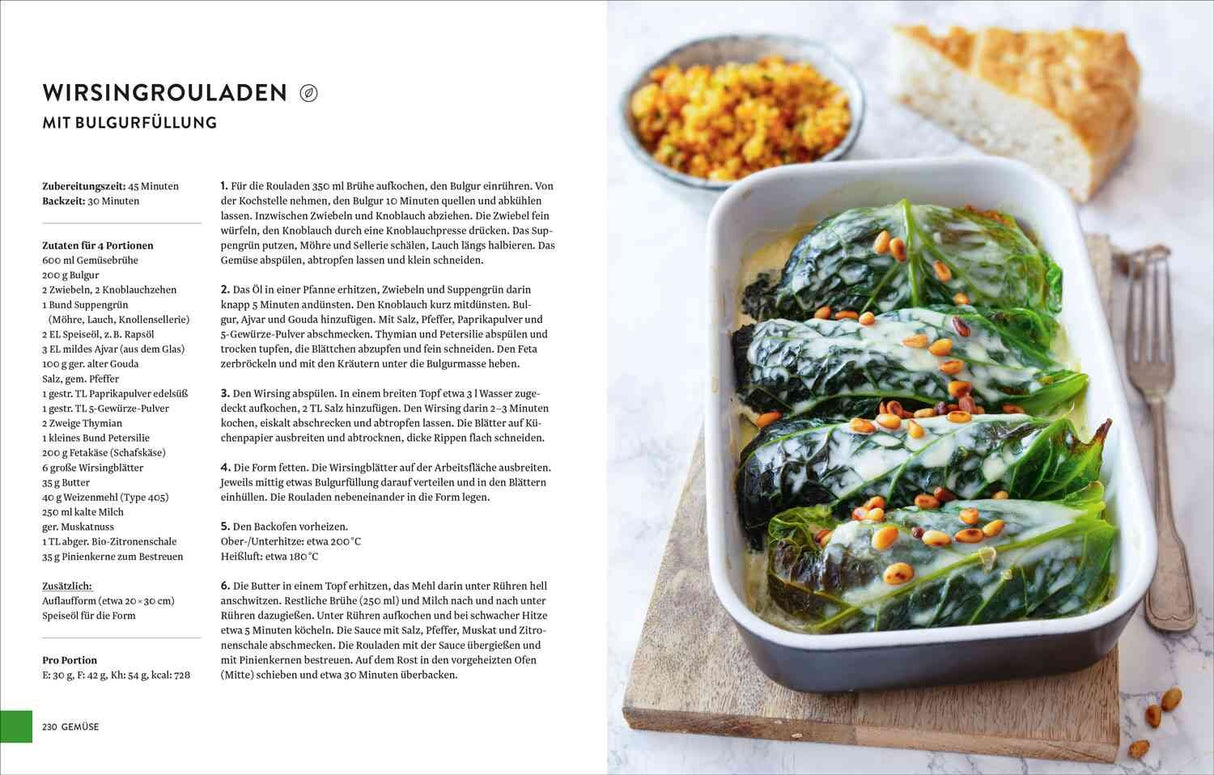 Auflauf mit gefülltem Wirsing, in einer weißen Auflaufform, mit Pinienkernen bestreut, auf Holzbrett, daneben Gabel und Kuchenstüc