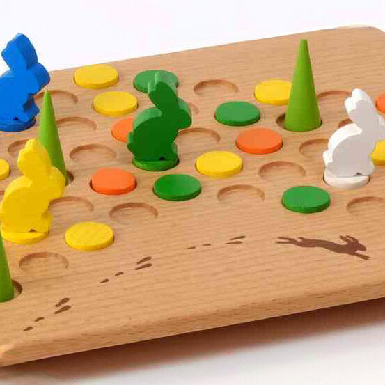 Holzspiel mit bunten Figuren, runden und spitzen Elementen, auf einer Spielfläche mit Tier- und Fußabdruck-Motiven.