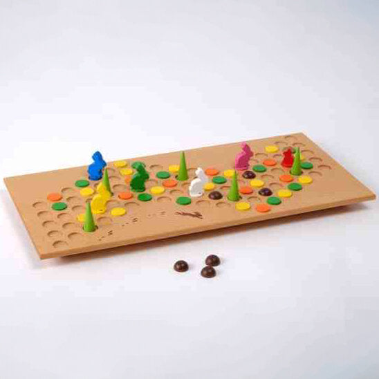 Brettspiel mit bunten Figuren, Spielsteinen und zwei schwarzen Kugeln auf weißem Hintergrund.