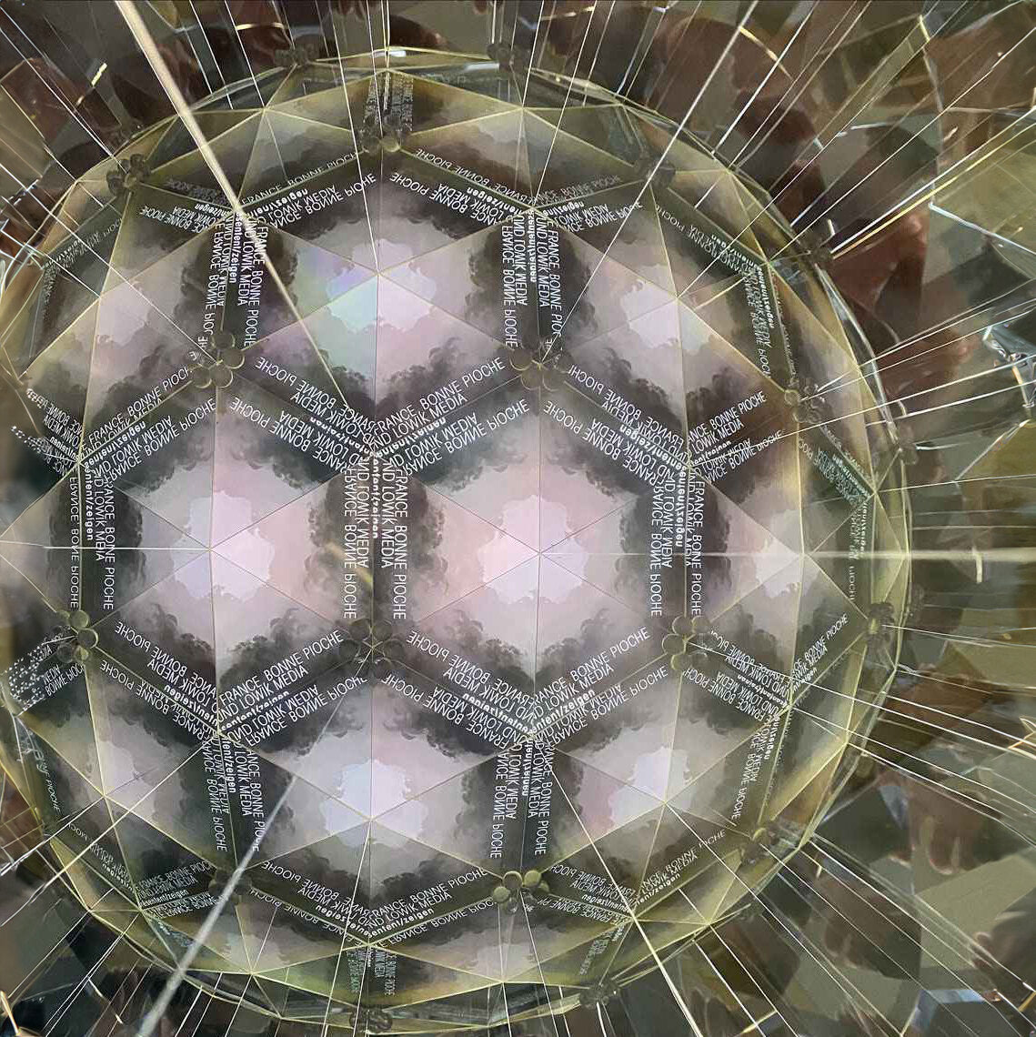 Kaleidoskopartige Spiegelung mit Text "Bonne Pioche, Low Media" in schwarzem und weißem Muster.