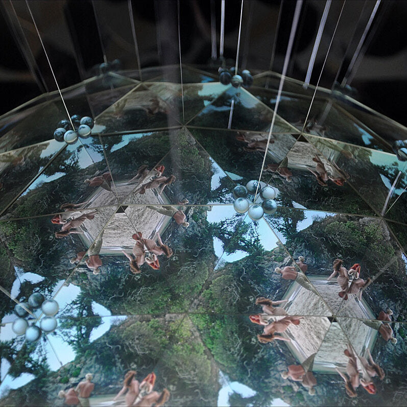 Reflexionen von Menschen, Bäumen und Himmel in einer spiegelnden, geometrischen Oberfläche.