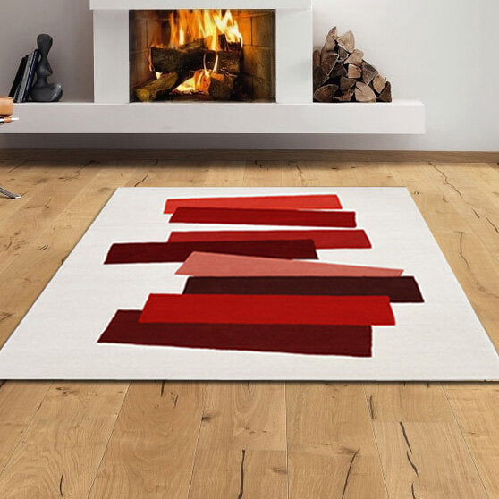 Weiße Teppich mit roten und pinken Streifen vor Kamin mit Feuer und Holzstapel.