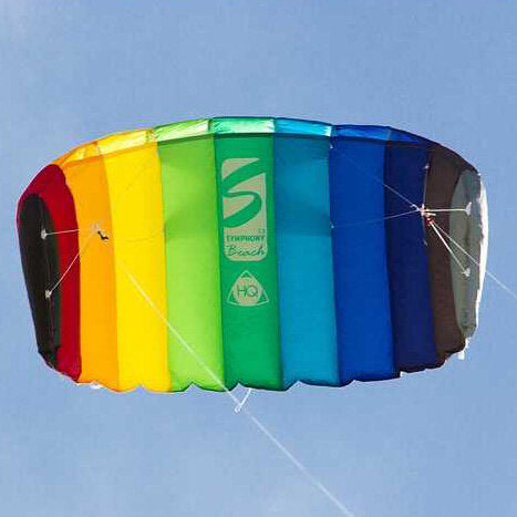Dreifarbiges, bunter Kite mit Regenbogenfarben fliegt am blauen Himmel.