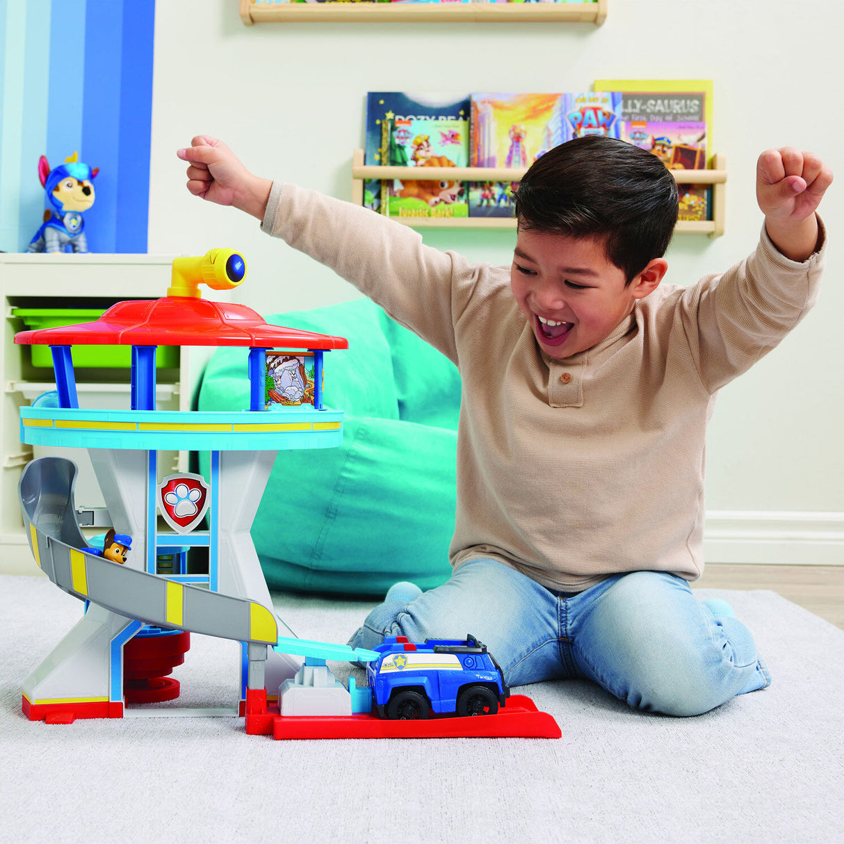 Junge spielt mit Paw Patrol Spielzeug, jubelt und hebt die Arme.