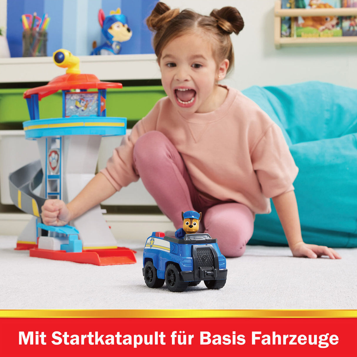 Ein Mädchen spielt mit Paw Patrol Spielzeug, vor einem blauen Sofa, im Kinderzimmer.