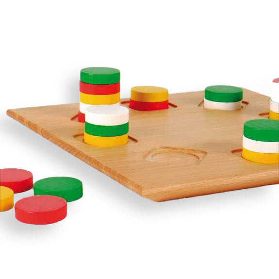 Holzspielbrett mit gestapelten bunten Ringen in Rot, Grün, Weiß und Gelb, einige Ringe liegen daneben.