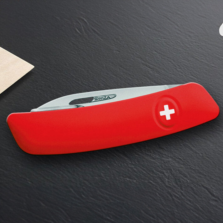 Rotes Schweizer Taschenmesser mit weißem Kreuz auf einem Tisch.