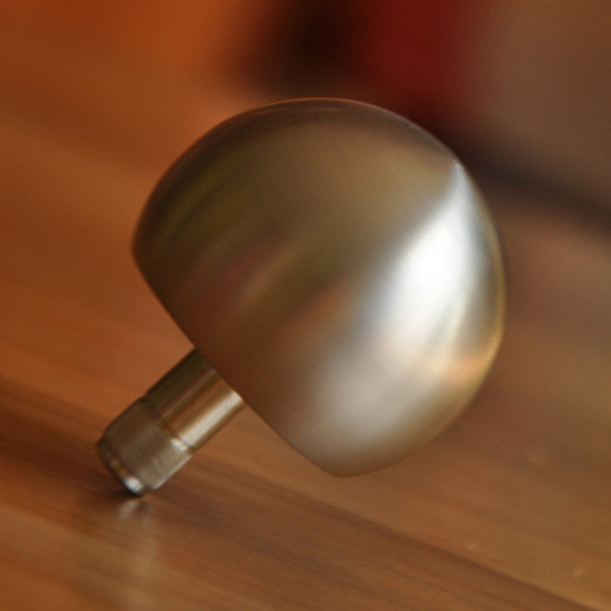 Metallknopf auf Holzoberfläche, Nahaufnahme, unscharfer Hintergrund.