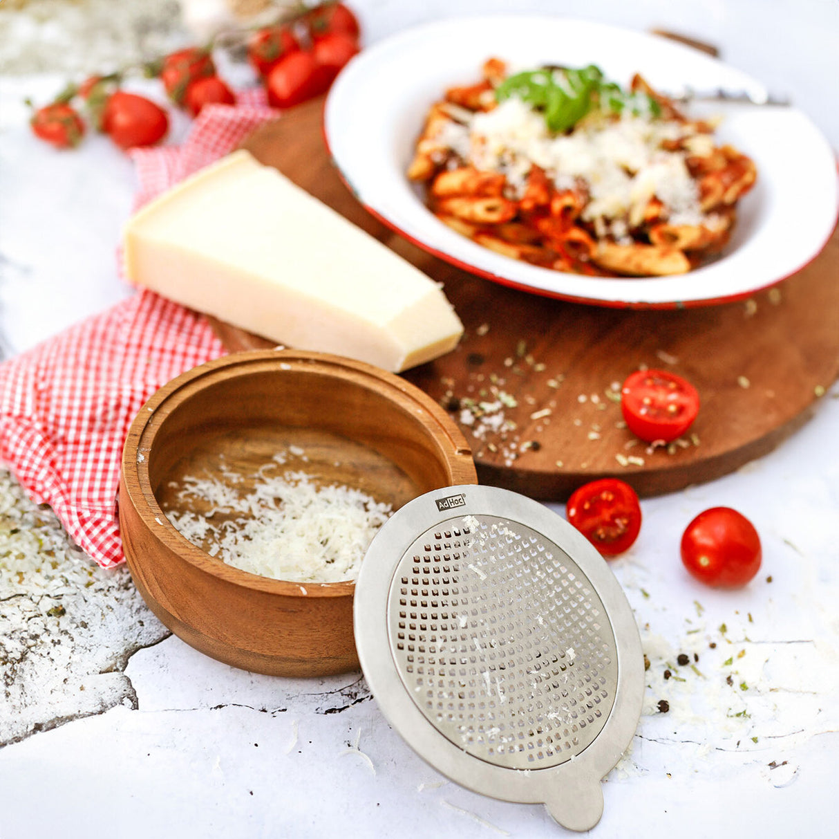 Pasta mit Tomatensauce, Parmesan, Tomaten, Käse, Reibe, Holzbrett, rote und weiße Tischdecke.