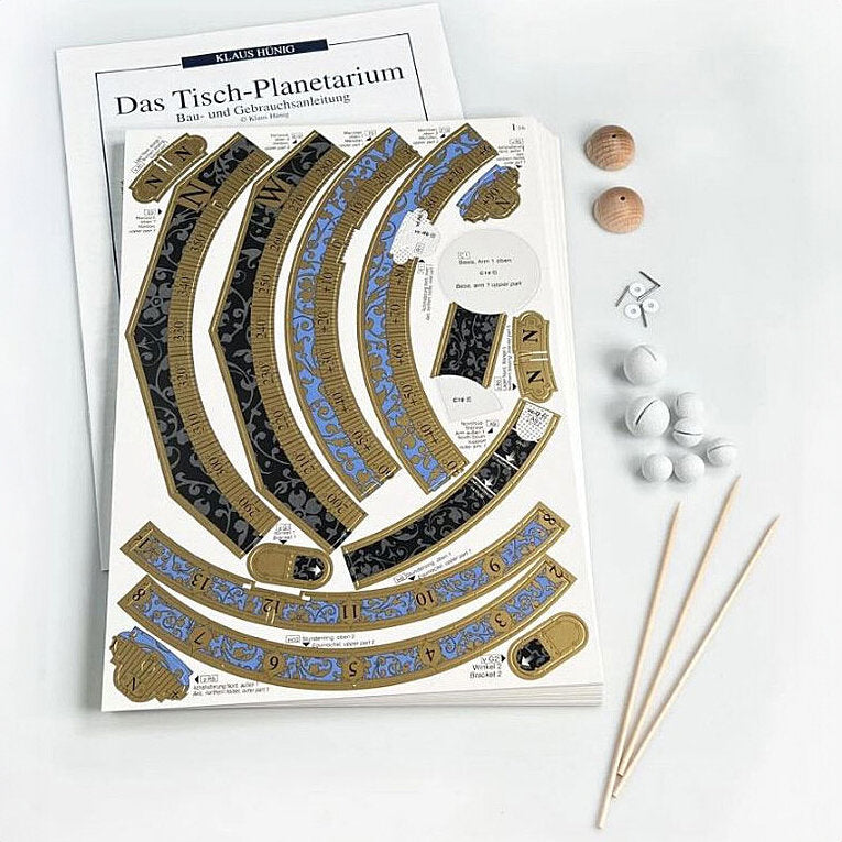 Bauanleitung für ein Tisch-Planetarium, Holzstücke, Schienen, Kugeln, Klammern und Holzstäbchen auf weißem Hintergrund.