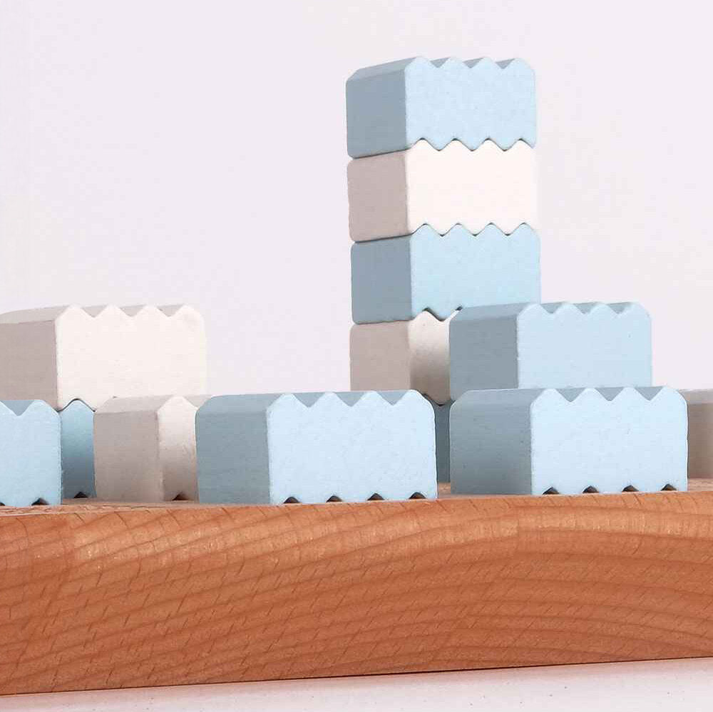 Holzspielzeug in Form von Blöcken in Weiß und Blau, auf einer Holzschale.