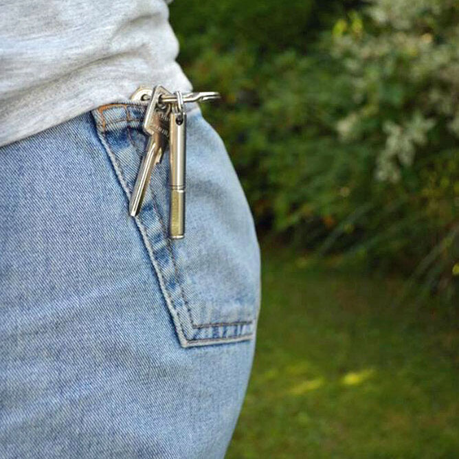 Hüftbereich einer Person in Jeans mit mehreren Schlüssel an der Gürtelschlaufe, im Hintergrund grüne Natur.