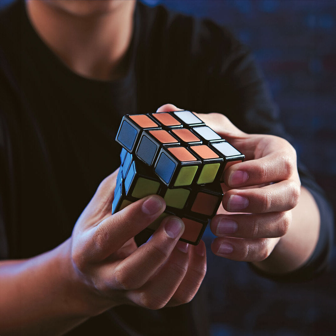 Person hält einen aufgeklickten Rubik's Cube mit blauen, grünen, orangefarbenen und weißen Flächen.