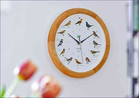 Runder Wand-Uhr mit Vogelmotiven und schwarzen Uhrzeigern an weißer Wand.