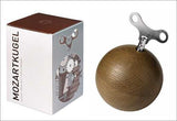 Box mit "Mozartkugel" und Holz-Kugel mit Metall-Teil oben.