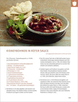 Gekochte Kidneybohnen in roter Sauce in einer Schüssel, daneben frisches Fladenbrot, Koriander und Chili.